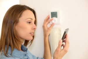 Pro Woman Regulating Thermostat With Smartphone Shutterstock 140835070 (1)